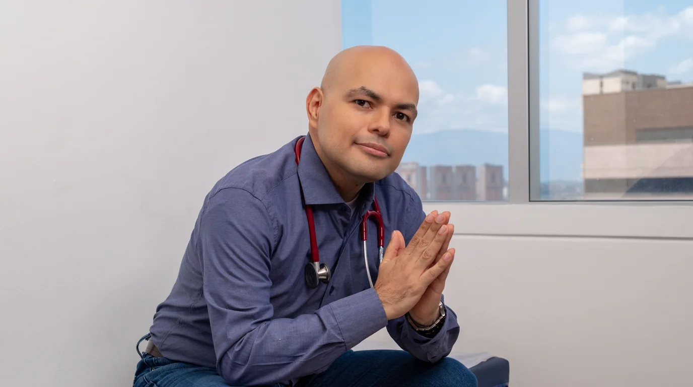 Dr. Daniel Amaya con estetoscopio en su consultorio, con vista de Medellín de fondo